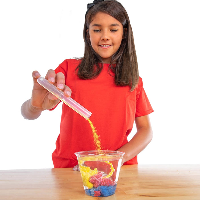 girl pouring magic sand into cup of water 